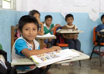Estudiantes colaborando en un aula con disposición grupal.