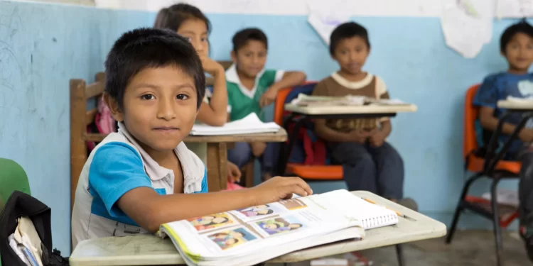 Estudiantes colaborando en un aula con disposición grupal.