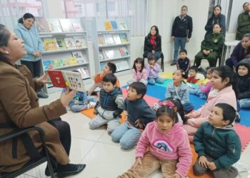 Niños escuchando atentamente a una persona adulta que les lee en voz alta.