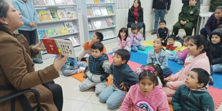 Niños escuchando atentamente a una persona adulta que les lee en voz alta.
