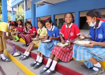 Niñas y niños comen alimentos frescos en una escuela como parte de un programa de nutrición escolar.