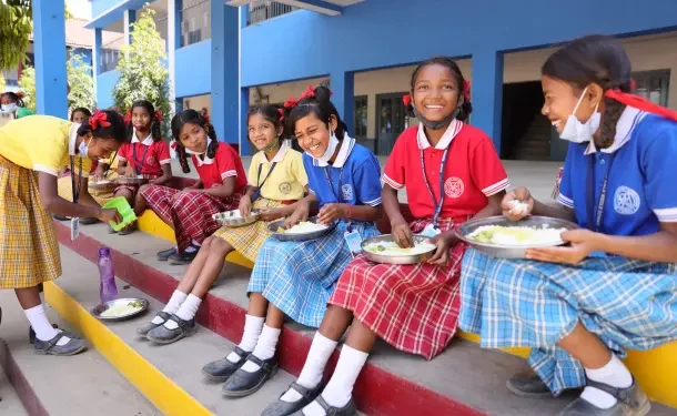 Niñas y niños comen alimentos frescos en una escuela como parte de un programa de nutrición escolar.
