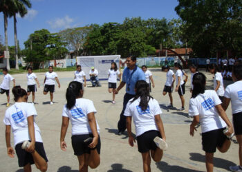 Niños en uniforme escolar participando en rutina de ejercicio como parte del programa Vive Saludable.