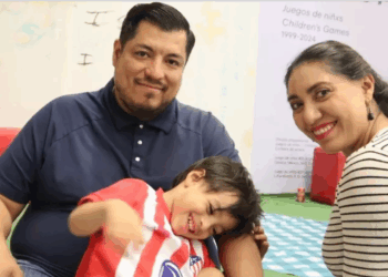 Niño jugando en un entorno escolar con adultos atentos.
