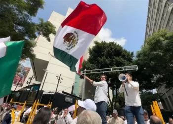 Estudiantes marchando frente a edificios universitarios con pancartas que exigen democracia en las decisiones institucionales