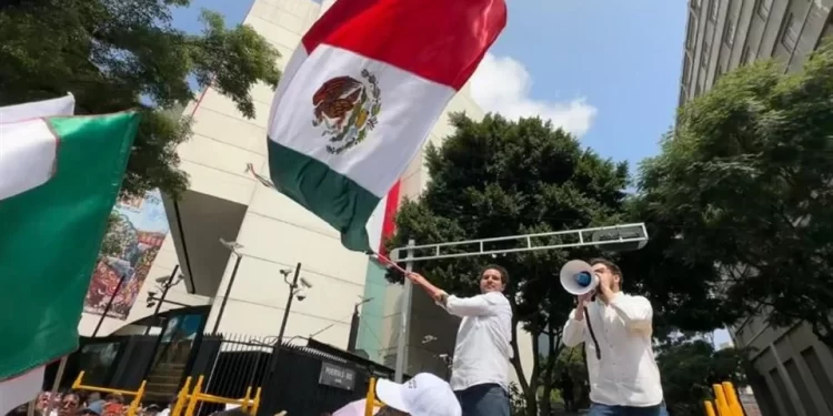 Estudiantes marchando frente a edificios universitarios con pancartas que exigen democracia en las decisiones institucionales