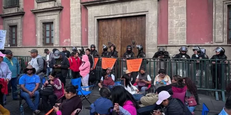 Fotografía de maestras y maestros de la CNTE en plantón frente a Palacio Nacional con pancartas por justicia laboral y social.