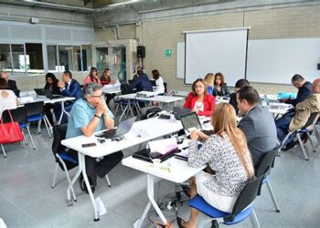 "Ilustración de docentes interactuando en un aula con elementos simbólicos que representan los imaginarios sociales sobre la docencia."