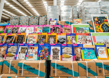 Libros gratuitos SEP apilados con las portadas visibles sobre cajas para repartirlos.